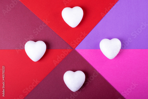 Geometric backdrop for Valentine's Day. White hearts against the pink, red and purple background. Flat lay