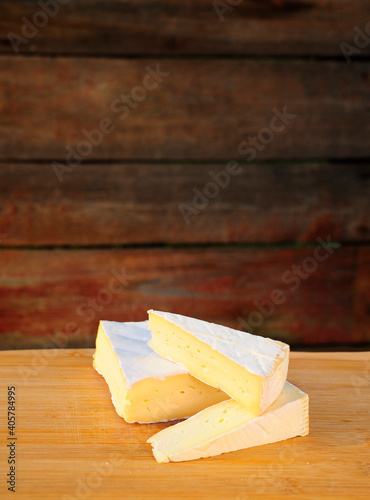 amembert cheese with a delicate texture, cut into large triangular pieces, lay on top of each other on a wooden background
