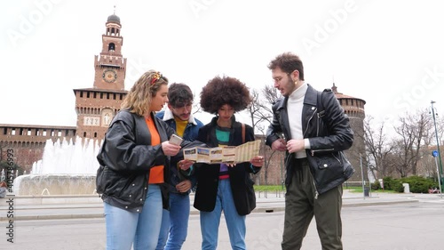 Slow motion four multiethnic friends traveller outdoor searching using tourist map guide sightseeing and discovering new places