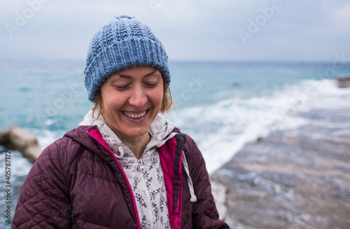 Portrait of a smiling girl in a knitted hat while walking along the sea coast © zhukovvvlad