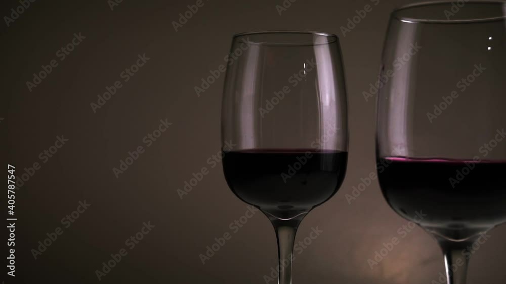 Red wine, in two glasses on a table against a dark background. Slow motion medium shot. High quality FullHD footage Red wine, in two glasses on a table against a dark background. Slow motion medium shot. High quality FullHD footage