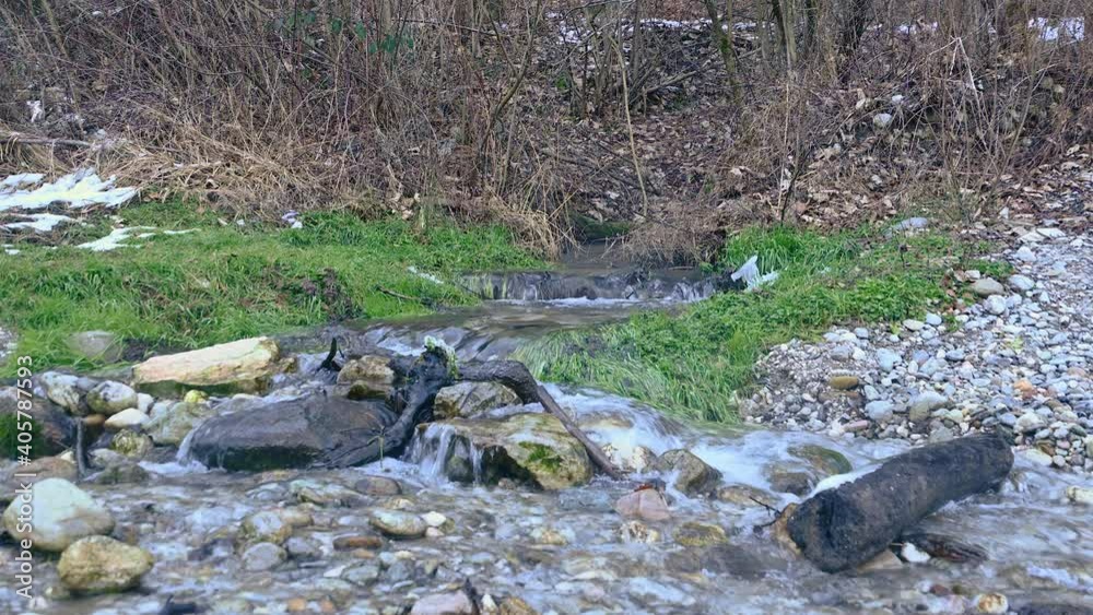 Small stream flowing in pristine nature. Low angle view of water flowing over rocks. Static shot, real time, wide angle Small stream flowing in pristine nature. Low angle view of water flowing over rocks. Static shot, real time, wide angle