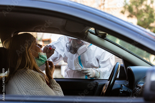 Medical worker in PPE performing drive-thru COVID-19 test © MexChriss