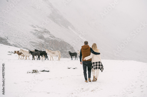 A couple of lovers go to a herd of horses in the fall in Altai