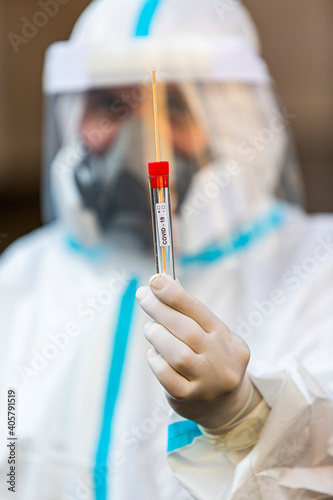 Medical worker in PPE holding COVID-19 test
