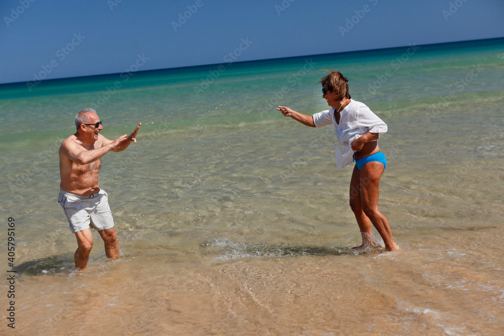 Coppia di anziani , gioca e si diverte sulla riva di una spiaggia in abbigliamento estivo Coppia di anziani , gioca e si diverte sulla riva di una spiaggia in abbigliamento estivo