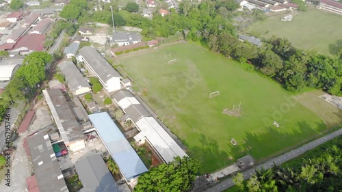 School Soccer Field With Bushes And Trees Beside It Under The Hot Sun - Aerial Tilt Down 