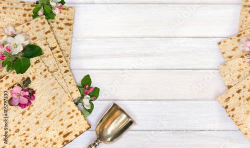Matzo, silver bowl and pink flowers apple tree for passover celebration on background white wooden planks with space for text. Top view, flat lay
