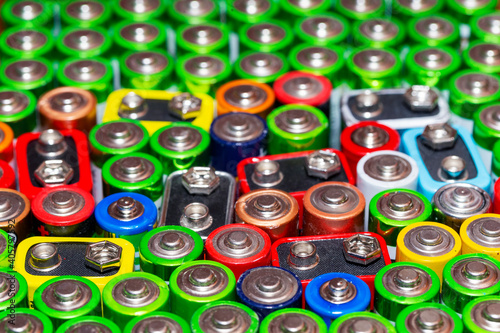 Used alkaline batteries AA size format of different brands lying in a rows. top view background texture of electric batteries and accumulators AA. AA packed close to each other. Used AA batteries