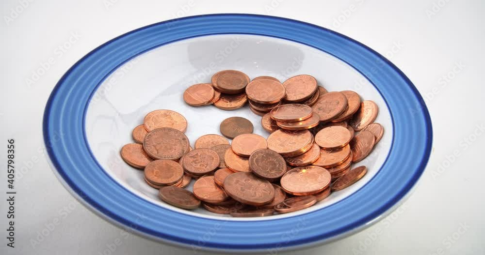 Waste of money. POV eating the British money penny coins with left hand spoon from plate on a white background. Waste of money. POV eating the British money penny coins with left hand spoon from plate on a white background.