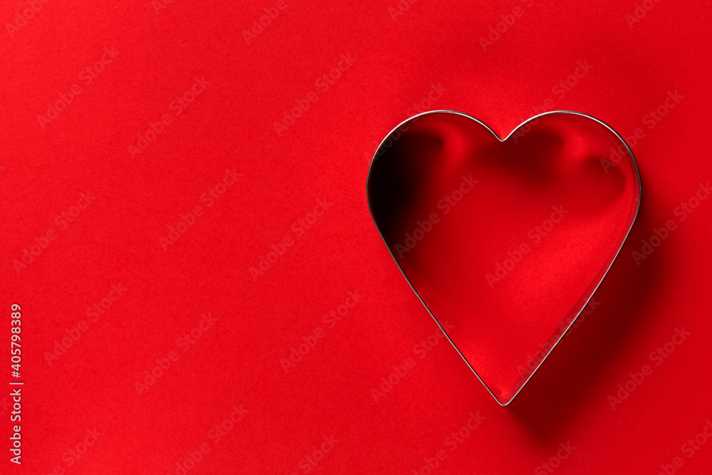 Saint Valentine day minimalistic greeting card, heart-shaped cookie cutters on red background with beautiful shadows