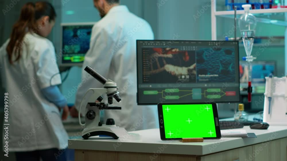 Tablet with green screen working in labooratory with mock up, chroma key display while professional engineer testing virus evolution in background. High tech development lab with blood samples Tablet with green screen working in labooratory with mock up, chroma key display while professional engineer testing virus evolution in background. High tech development lab with blood samples
