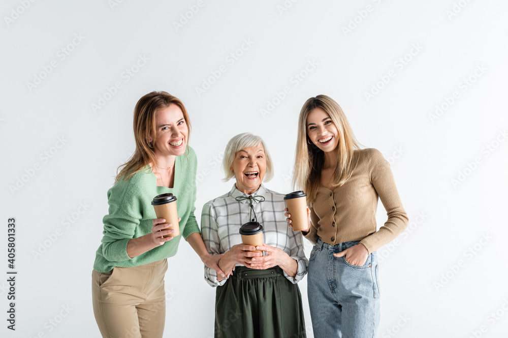 Fototapeta premium three generation of cheerful women holding paper cups isolated on white