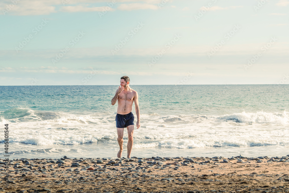 Athletic young man walking on a beach in Gran Canaria during Covid after a swim in Atlantic Ocean
