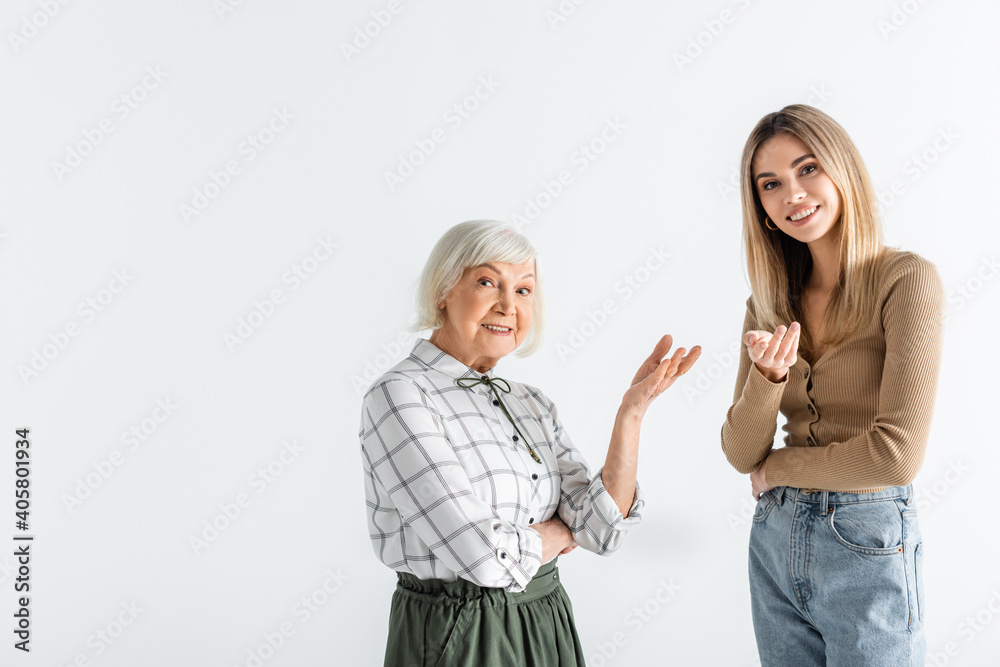 happy granddaughter and granny standing and pointing with hands isolated on white