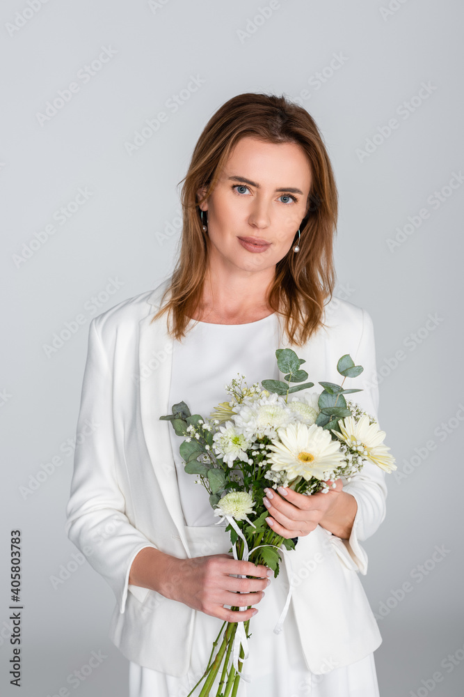 woman holding bouquet of flowers and looking at camera isolated on grey woman holding bouquet of flowers and looking at camera isolated on grey