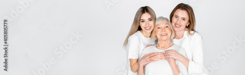 three generation of happy women smiling while looking at camera isolated on grey, banner photo