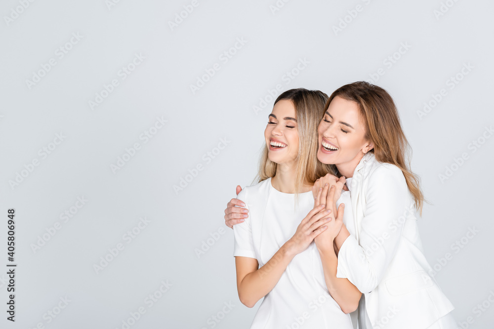 happy mother hugging young daughter with closed eyes isolated on grey happy mother hugging young daughter with closed eyes isolated on grey