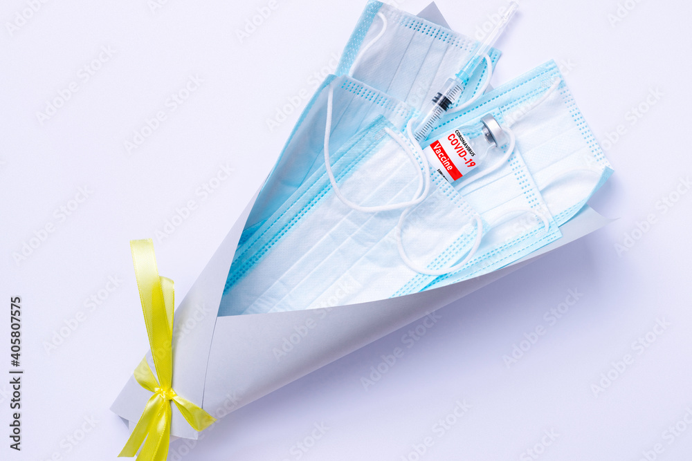 Covid-19 vaccine and disposable medical masks are wrapped in a bouquet with a jar on a white background. The most trending gift in the world. Covid-19 vaccine and disposable medical masks are wrapped in a bouquet with a jar on a white background. The most trending gift in the world.