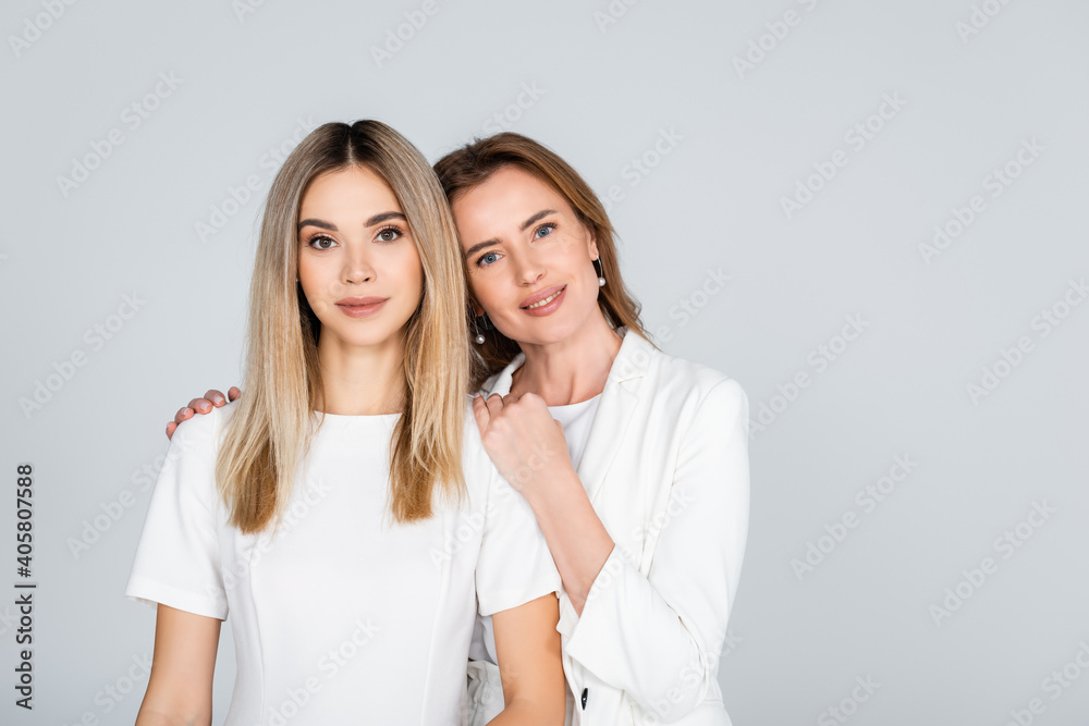 happy mother hugging young daughter isolated on grey happy mother hugging young daughter isolated on grey