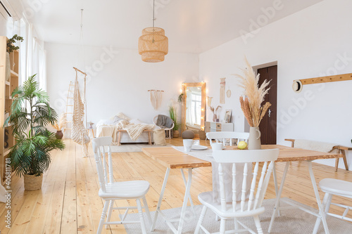 cute cozy light interior design of the apartment with a free layout of the kitchen and bedroom areas. a lot of windows  a wooden floor and a hanging swing.