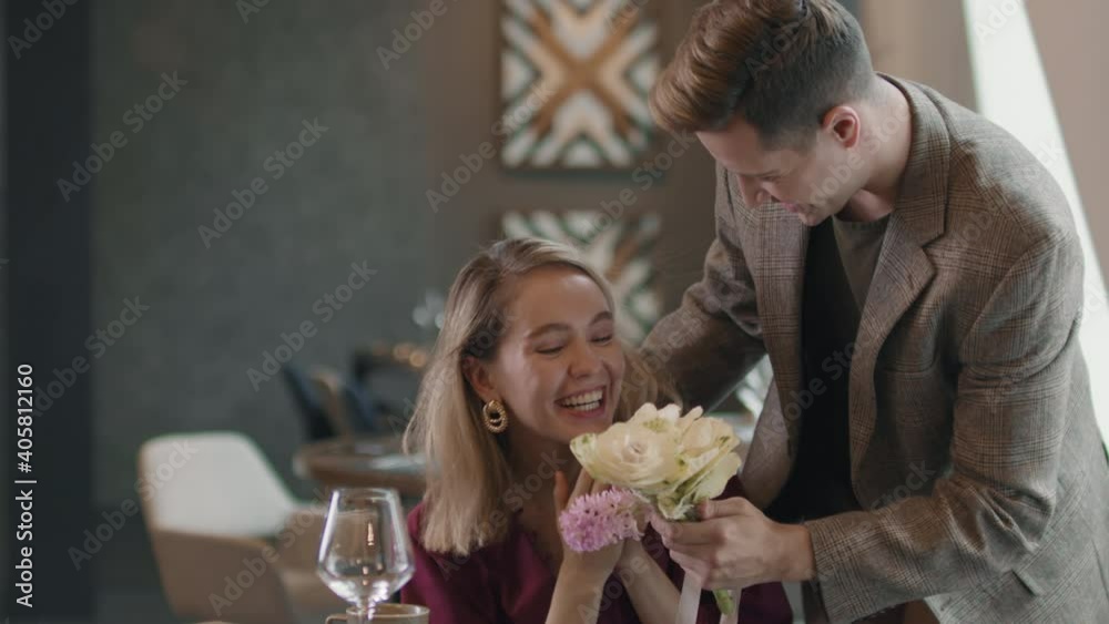 Medium shot of man closing eyes from behind to beautiful woman sitting in cafe with cup of coffee waiting for him having date Medium shot of man closing eyes from behind to beautiful woman sitting in cafe with cup of coffee waiting for him having date