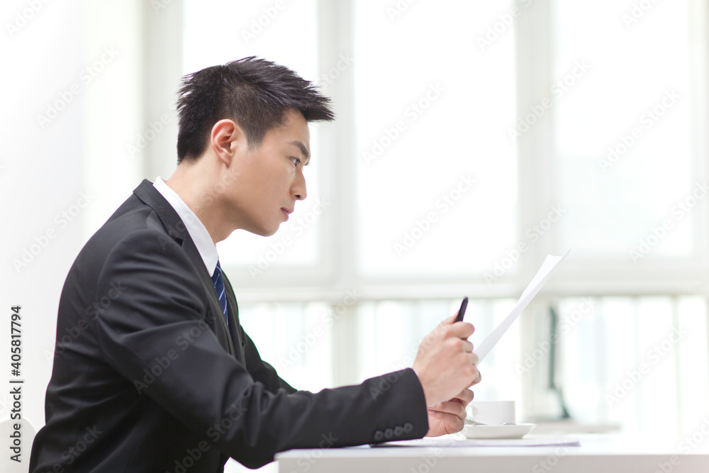 Portrait of young businessman at desk looking documents Portrait of young businessman at desk looking documents