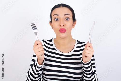 Model hungry Young beautiful woman wearing stripped t-shirt against white background holding in hand fork knife want tasty yummy pizza pie