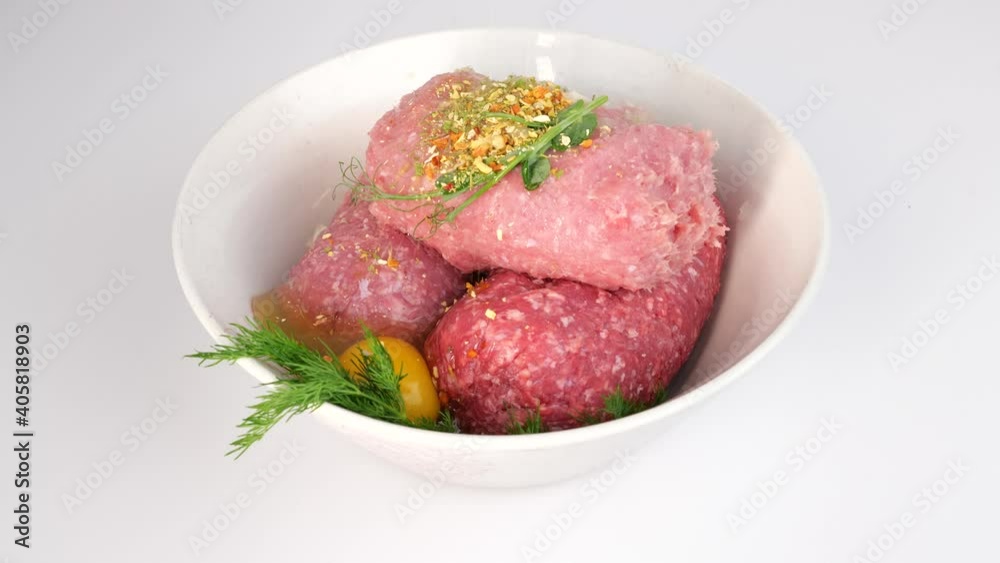 Close-up of adding herbs and spices to fresh mixed minced meat in a white bowl. Cooking Process of preparing cutlets, 4K, slow motion Close-up of adding herbs and spices to fresh mixed minced meat in a white bowl. Cooking Process of preparing cutlets, 4K, slow motion