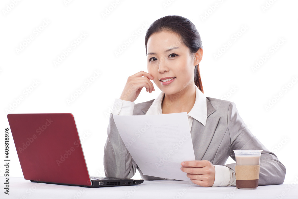 Smiling businesswoman holding paper in front of a laptop Smiling businesswoman holding paper in front of a laptop