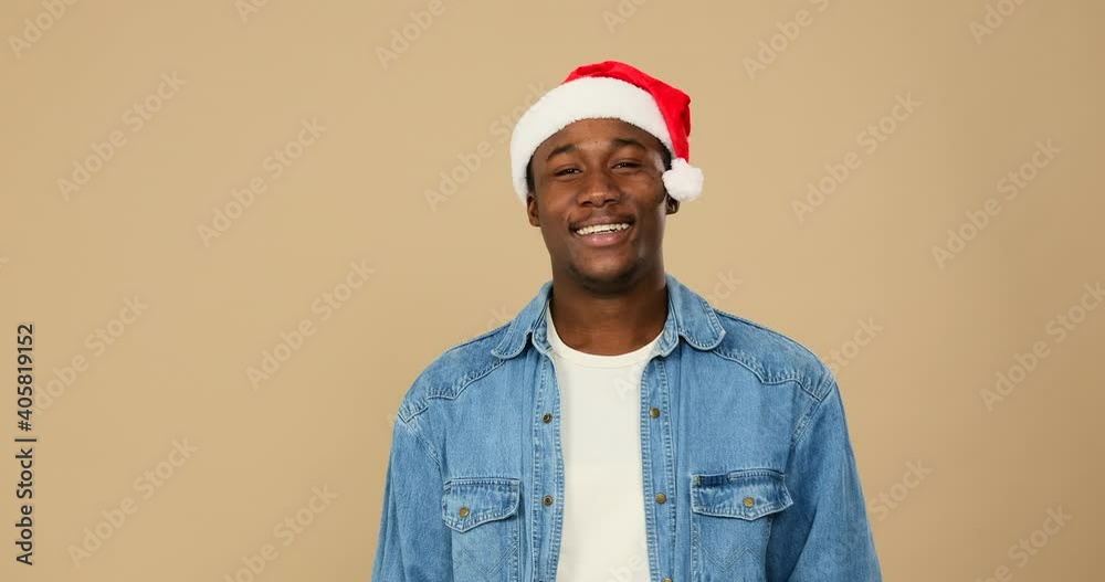 Man in santa hat showing ok gesture with hand over beige background Man in santa hat showing ok gesture with hand over beige background