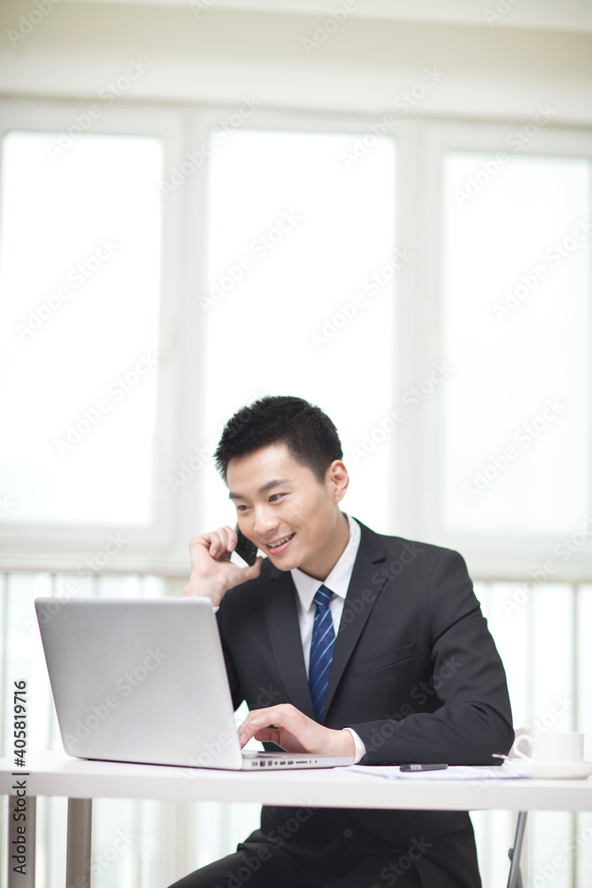 Portrait of businessman sitting at desk and using cell phone Portrait of businessman sitting at desk and using cell phone