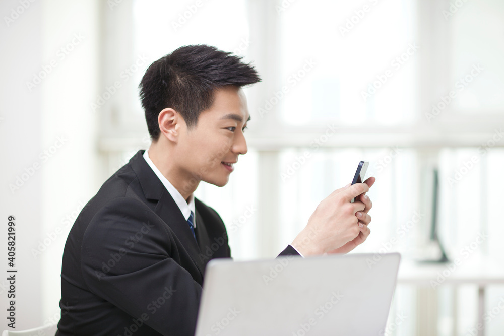 Portrait of businessman sitting at desk and looking at cell phone Portrait of businessman sitting at desk and looking at cell phone