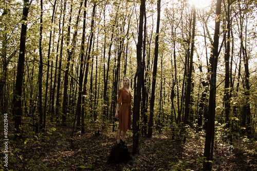 Portrait of a beautiful mysterious woman in dress with blond hair in the forest. like a fairytale. Warm tone