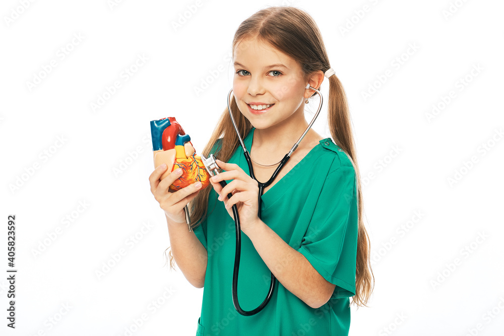 Concept of cardiac health and diagnosis of children's heart disease. Teenage girl listens to a heart model using a stethoscope Concept of cardiac health and diagnosis of children's heart disease. Teenage girl listens to a heart model using a stethoscope