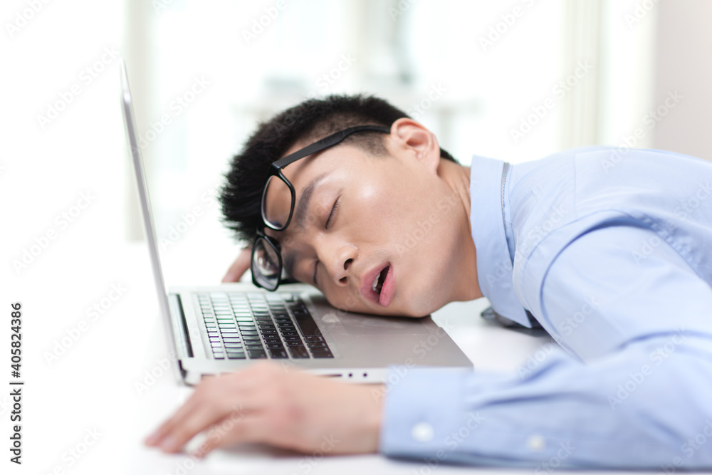 Portrait of young businessman sleeping on laptop by desk,close-up Portrait of young businessman sleeping on laptop by desk,close-up