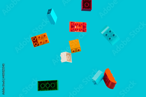 Pile of children's building blocks in several colors on a blue background