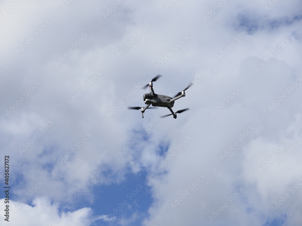 a drone flying in a blue sky with clouds a drone flying in a blue sky with clouds