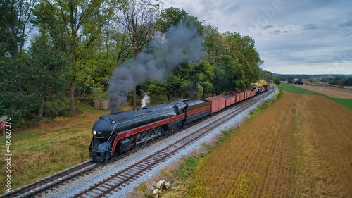 Aerial View of a Restored Antique Steam Engine and Passenger Cars Steaming Up at a Small Rail Road Station on a Summer Day