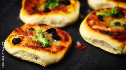 Selective focus. Appetizing mini pizzas on a dark background.