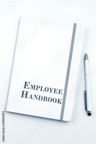 White Employee Handbook or manual with White pen on white table surface - personnel management policy, explains business goals, results, defines Leadership practices