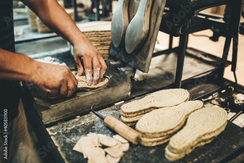 Manos trabajando en fábrica. Suelas de calzado de yute. Industria.