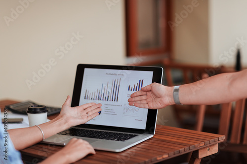 employees pointing at the laptop screen with financial data .