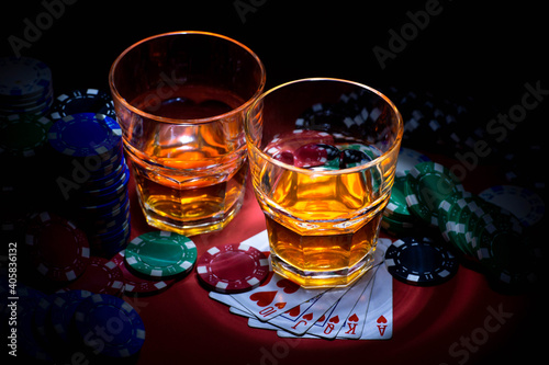 Casino. Poker. Game chips lie next to glasses of Whiskey on the table against a red background. Game chips for betting in gambling. Poker chips.