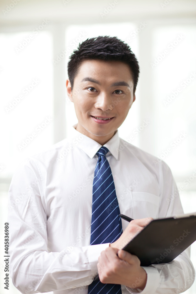 Portrait of young businessman writing in office,close-up Portrait of young businessman writing in office,close-up