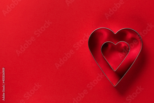 Saint Valentine day minimalistic greeting card, heart-shaped cookie cutters on red background with beautiful shadows
