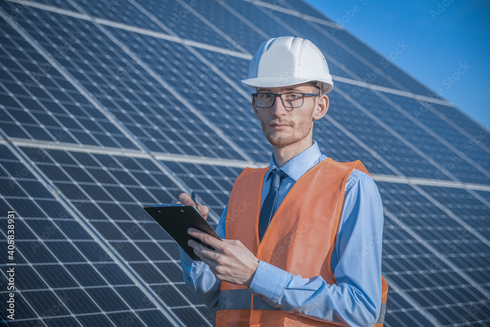 Engineer in uniform standing on a background of solar panels.The solar farm check the operation of the system, Alternative energy to conserve the world's energy, Photovoltaic module idea clean energy 