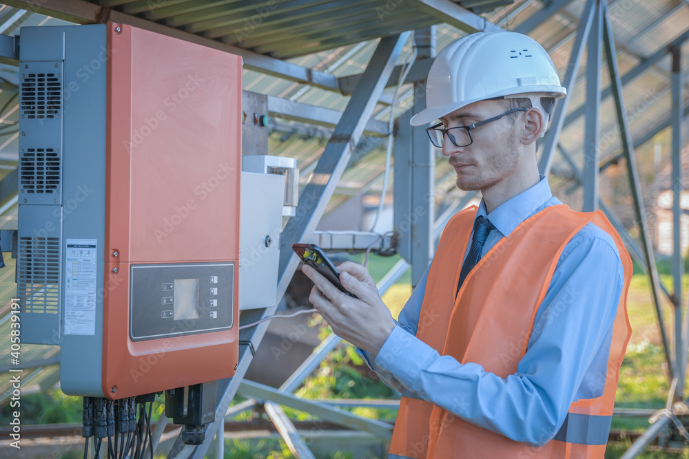 Engineer, a man in uniform checks the control system of the solar station on the background of solar panels Engineer, a man in uniform checks the control system of the solar station on the background of solar panels
