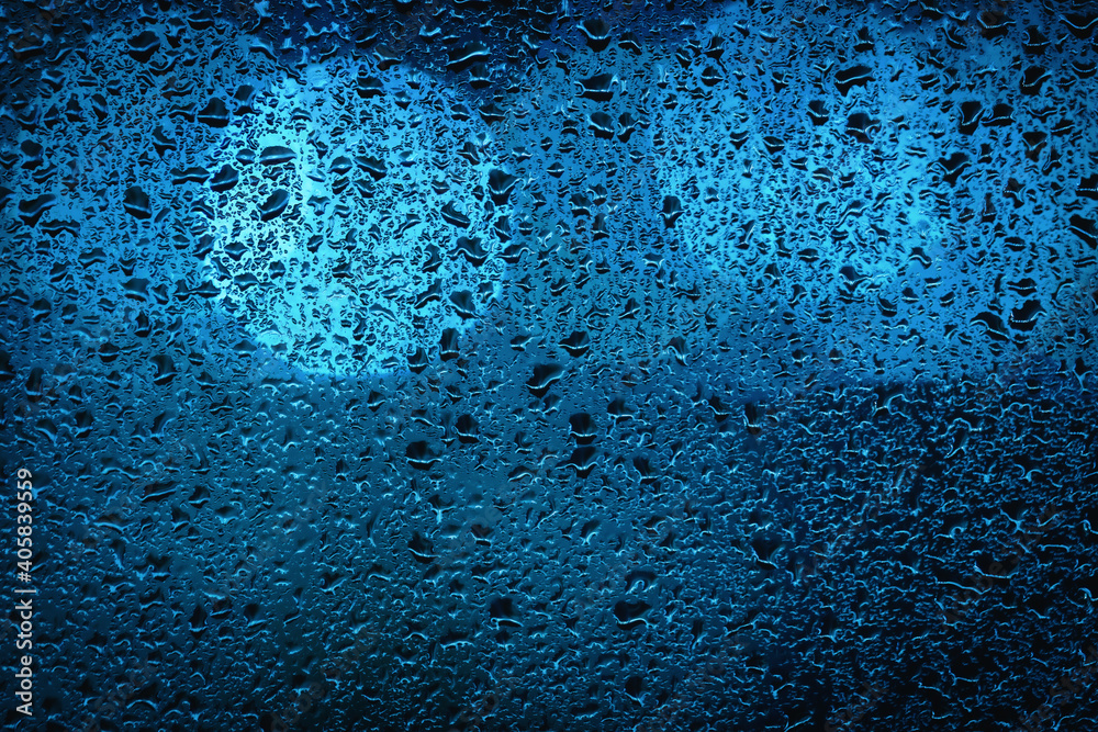 Blue bokeh lights behind a wet window