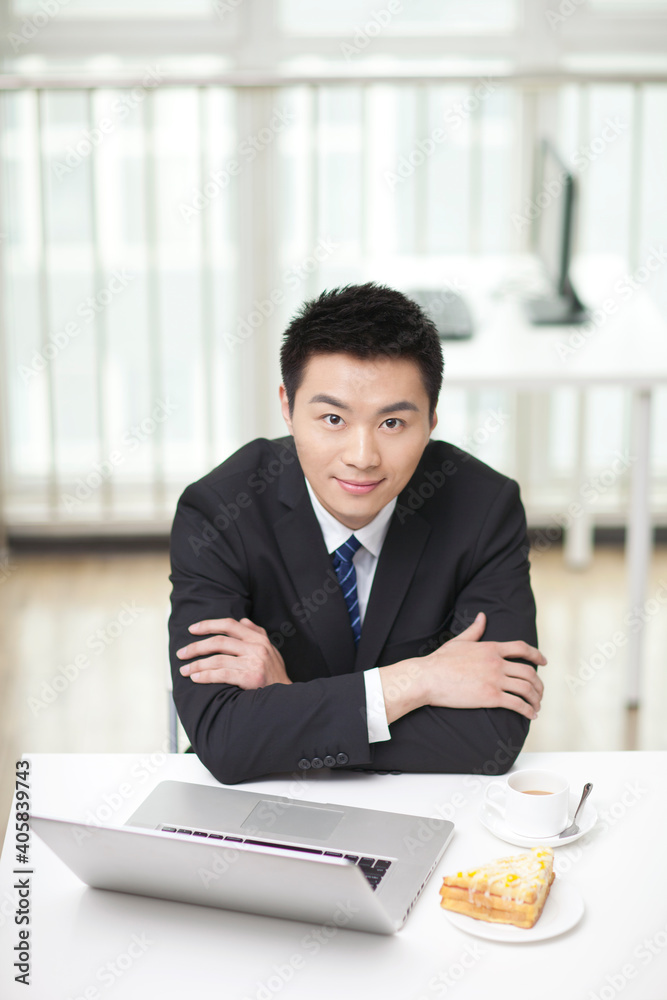 Portrait of businessman sitting at desk by laptop Portrait of businessman sitting at desk by laptop